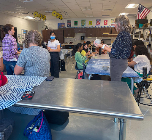 Vina Jumper, one of Denmarks art teachers, demonstrates how to create a pinch pot to the memebrs of NAHS.