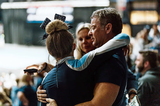 Father embraces his daughter in support at the state cheer competition.
