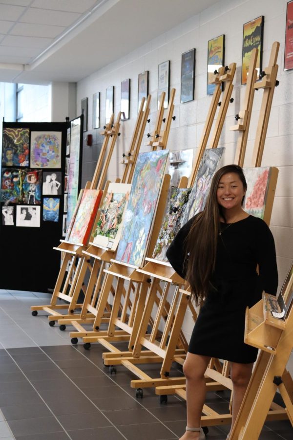 One of the art teachers, Ms. Wood, stands proud with the works of her students.