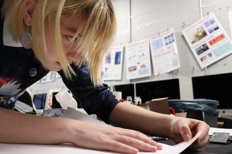 Junior Lilly Cody works diligently to place printed digital artwork onto a presentable board.