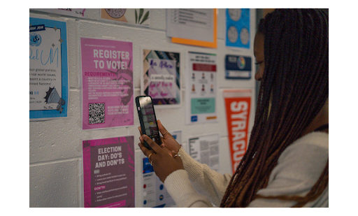 A poster in the hallway informs students about registering to vote. One senior scans a QR code with voter information, in hopes of using her voice in future elections.
