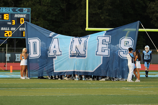 The Danes stand behind their banner, excited and waiting to be announced on the field for their homecoming game.